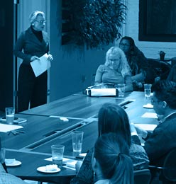 Filtered Photo of woman presenting to a table of listeners